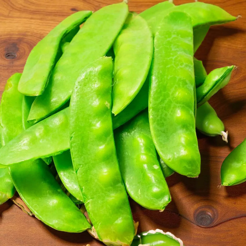 A pile of fresh green snap peas arranged on a bamboo mat.