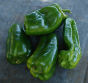 A group of fresh green bell peppers on a dark surface.