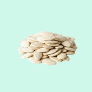 A pile of white pumpkin seeds against a light blue background.