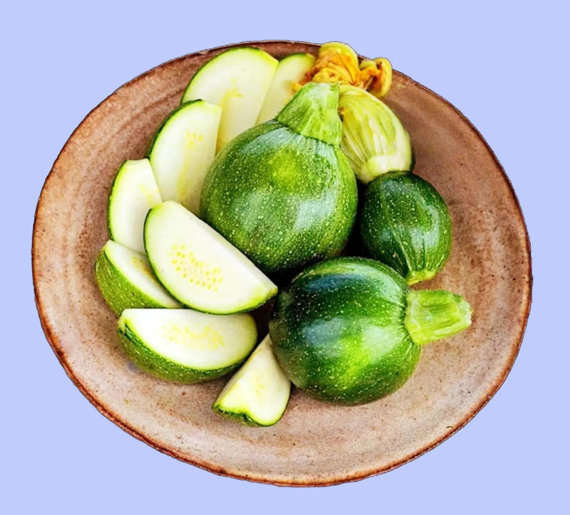 A plate of fresh green zucchini and sliced cucumbers is displayed on a dark background.