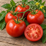 Early Girl tomatoes close-up showing several ripe medium-sized round deep red tomatoes whole and one sliced open showing bright juicy flesh on a rustic wood surface