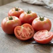 Smooth pink Bradley tomatoes beside a cut half showing juicy pink-red flesh