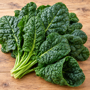 Winter Giant spinach freshly harvested large deeply savoyed dark green leaves arranged on a natural wood surface, showing prominent savoy texture and rich green color